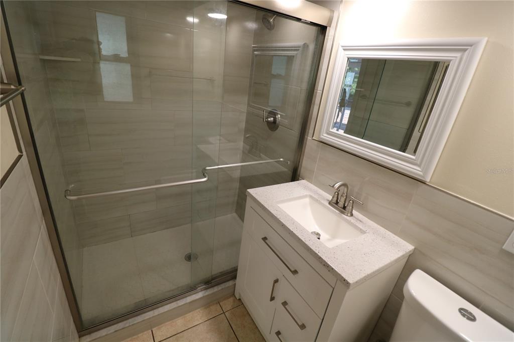 7825 Birchwood Drive Port Richey, FL 34668 - Photo 32 of 43 a bathroom with a sink a mirror and shower