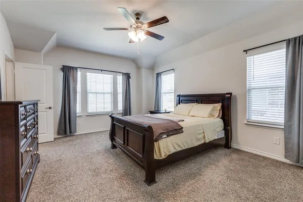 a bed sitting in a spacious bedroom next to a window