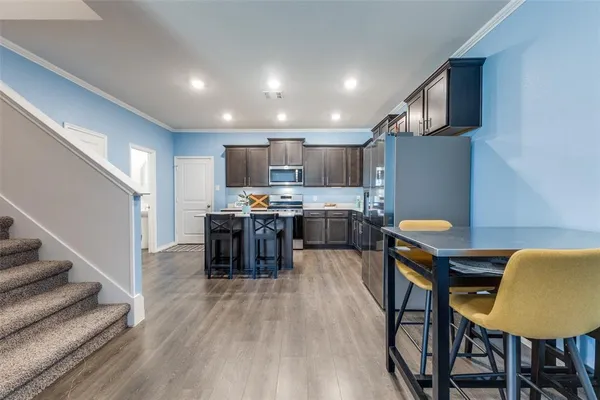 a living room with stainless steel appliances furniture a dining table and kitchen view