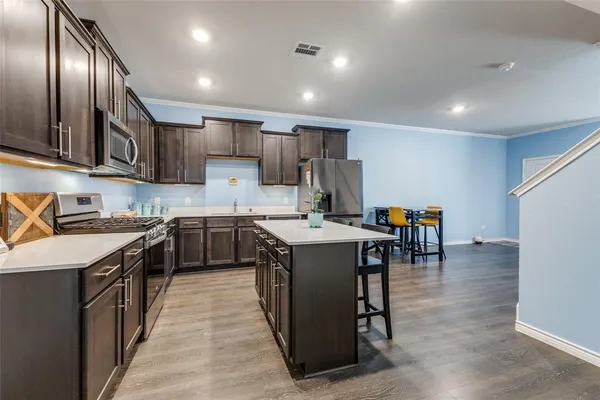 a kitchen with stainless steel appliances granite countertop a table chairs sink and cabinets