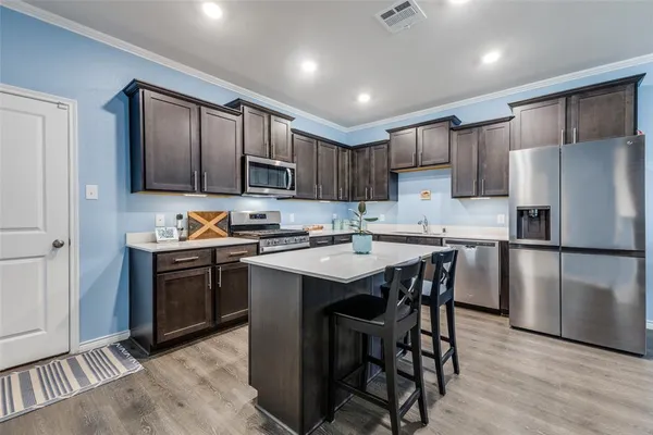 a kitchen with a refrigerator a stove a sink and a dining table with wooden floor