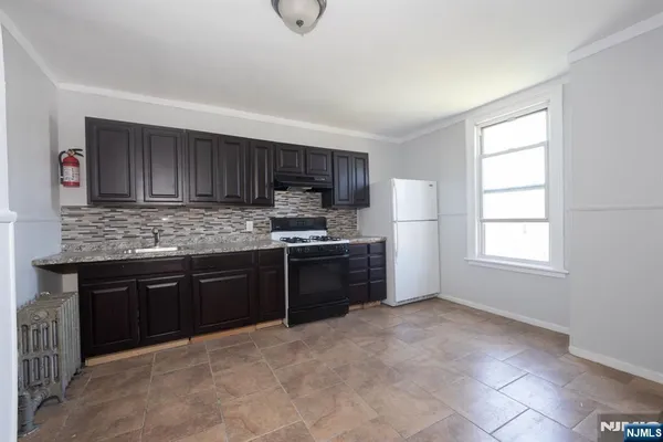 a kitchen with granite countertop a stove a sink a refrigerator and cabinets