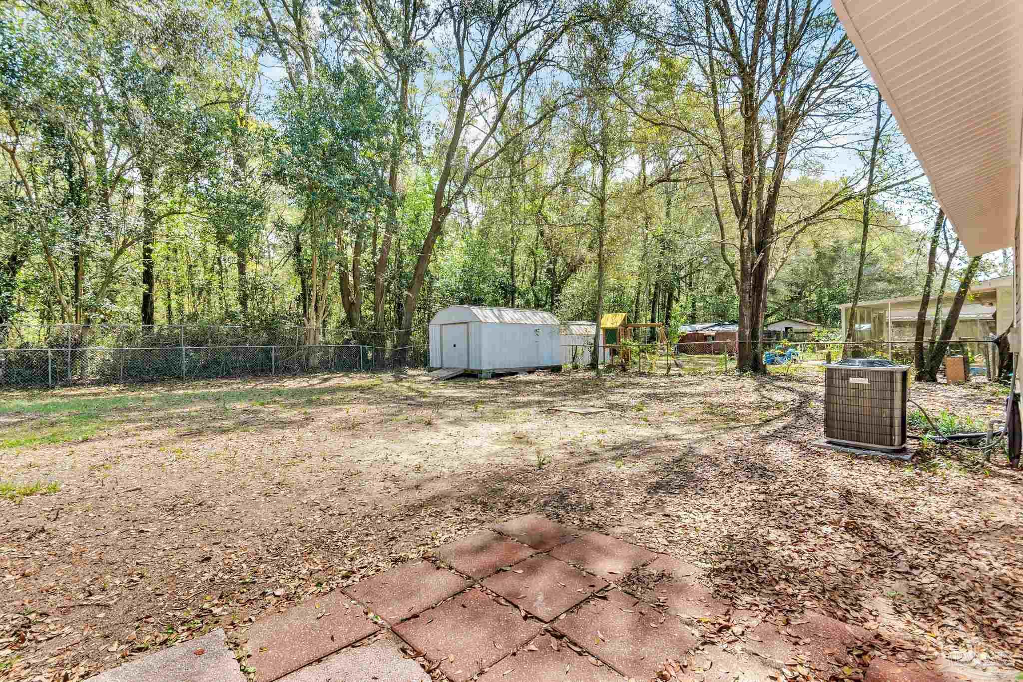 5636 Avondale Road Pensacola, FL 32526 - Photo 21 of 22 a backyard of a house with lots of green space and large trees