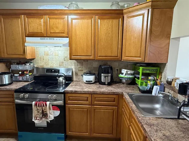a kitchen with stainless steel appliances granite countertop a sink a stove and a cabinets