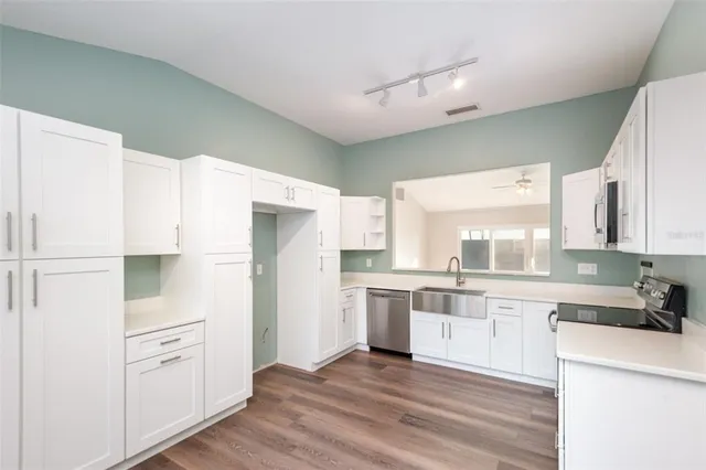 a kitchen with white cabinets and wooden floor