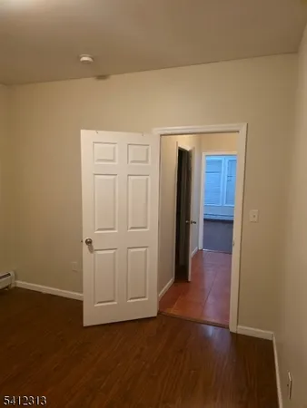 a view of an empty room with wooden floor and closet