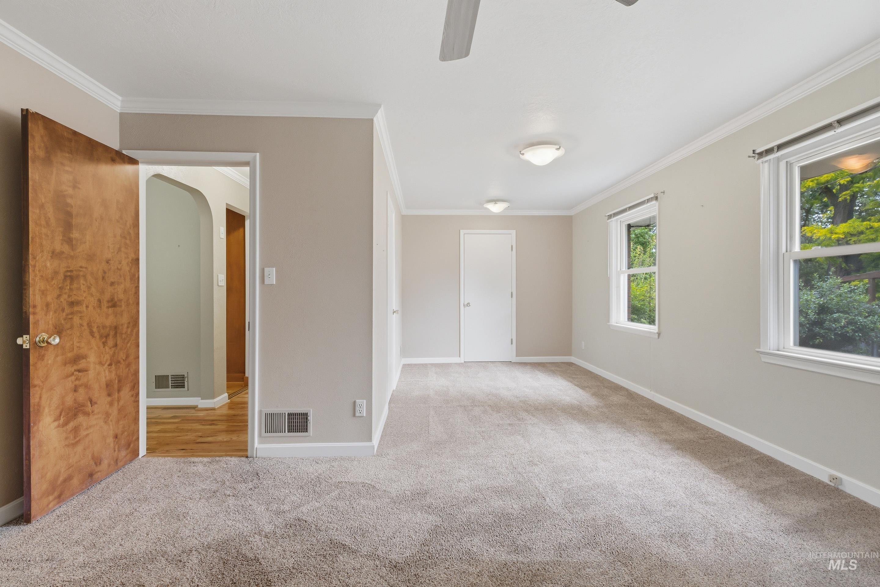 504 West Howe Street Boise, ID 83706 - Photo 25 of 47 Spacious room featuring neutral carpeting, crown molding, double windows, a ceiling fan, and two flush-mount light fixtures