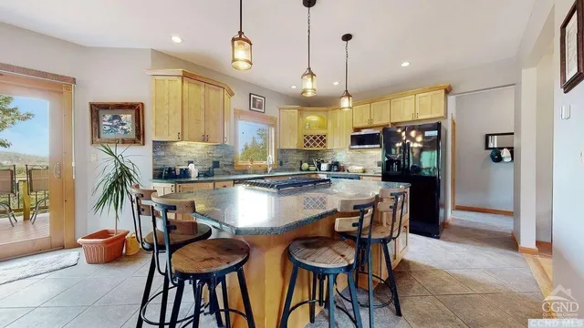 a kitchen with stainless steel appliances granite countertop a refrigerator a sink a stove and a dining table with wooden floor