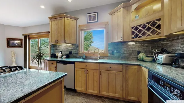 a kitchen with stainless steel appliances granite countertop a sink a stove and a wooden cabinets