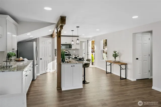 a kitchen with a refrigerator a stove top oven a sink dishwasher and white cabinets with wooden floor