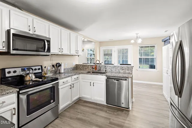 a kitchen with stainless steel appliances granite countertop a stove a sink dishwasher a refrigerator and a microwave