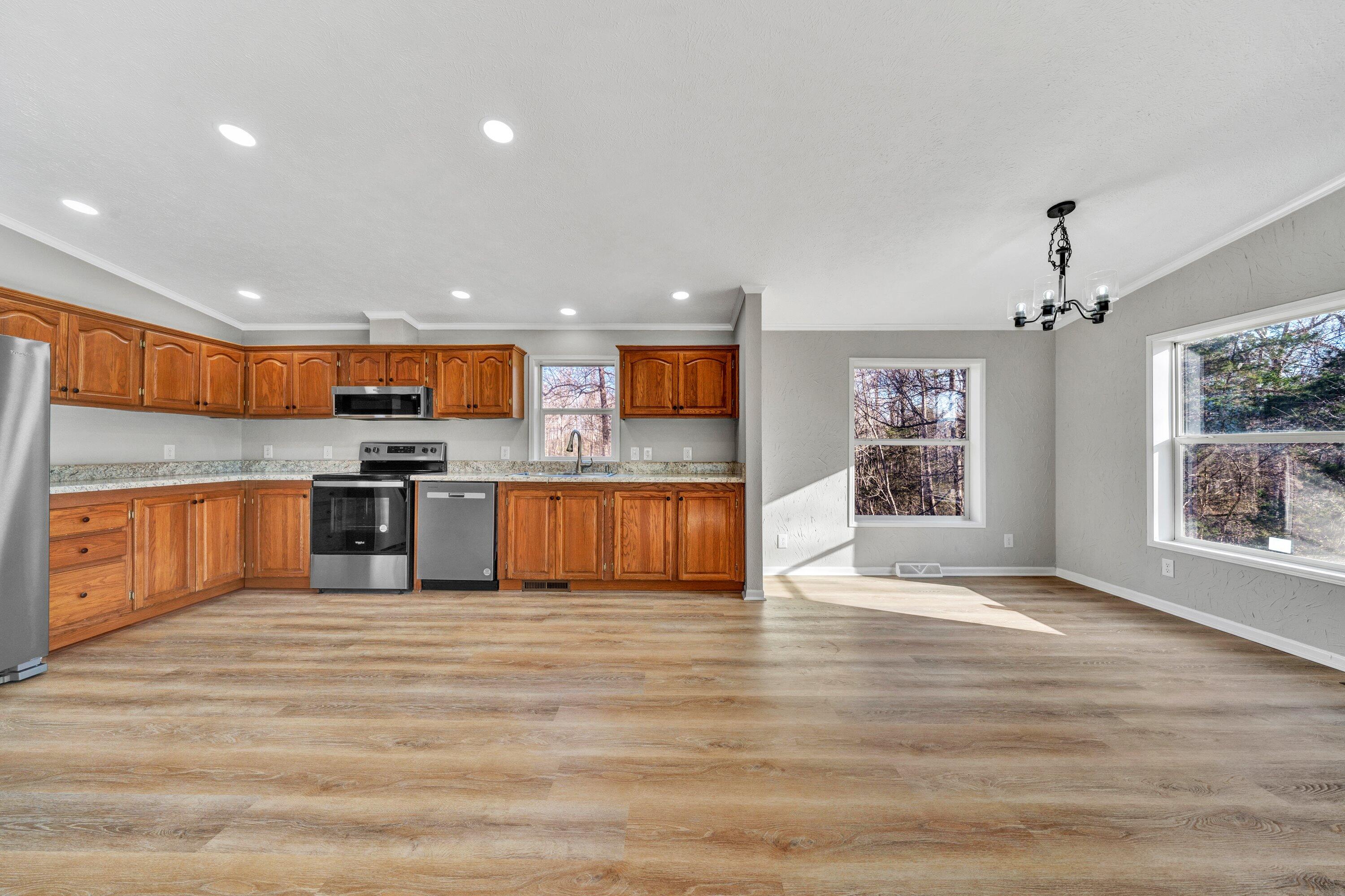 391 Jamestown Road Rocky Mount, VA 24151 - Photo 5 of 40 a large kitchen with stainless steel appliances granite countertop a stove top oven a sink dishwasher a microwave oven and a refrigerator with wooden floor