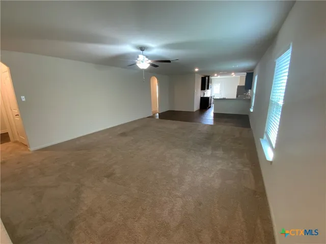 a view of a big room with windows and chandelier fan