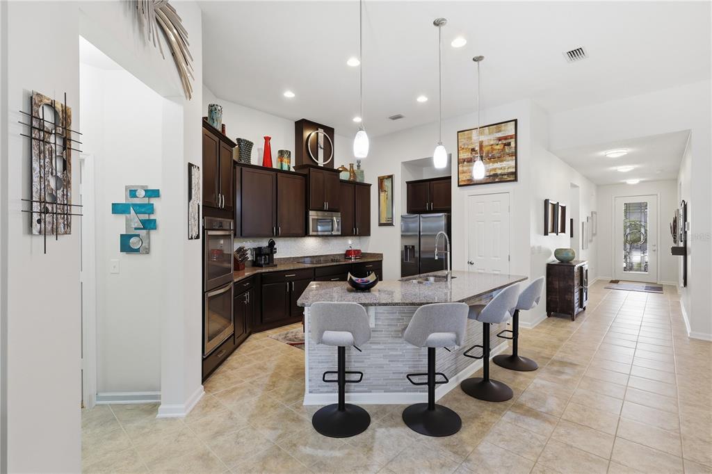 124 South Hummingbird Place Palm Coast, FL 32164 - Photo 6 of 47 a kitchen with stainless steel appliances kitchen island granite countertop a refrigerator a sink a stove and a dining table with wooden floor