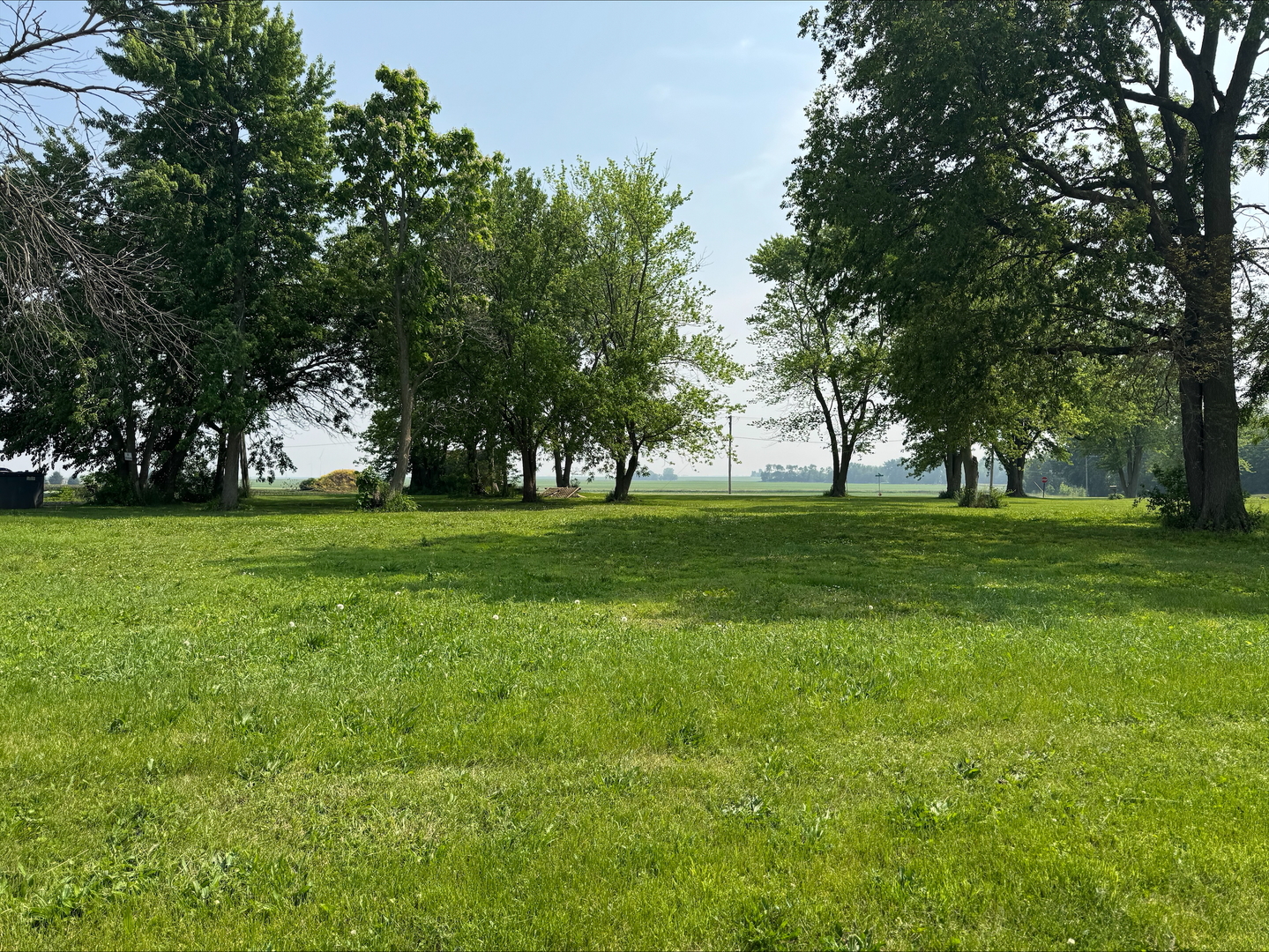 a view of grassy field with benches and trees all around