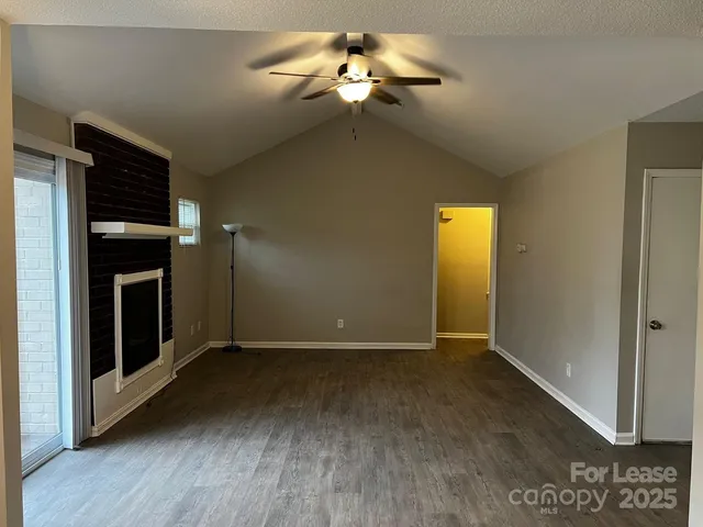a view of an empty room with chandelier fan and fire place
