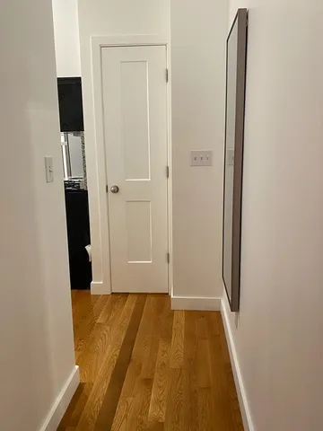 a view of a hallway with wooden floor and closet