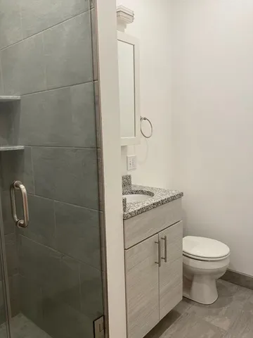 a bathroom with a granite countertop toilet and a sink