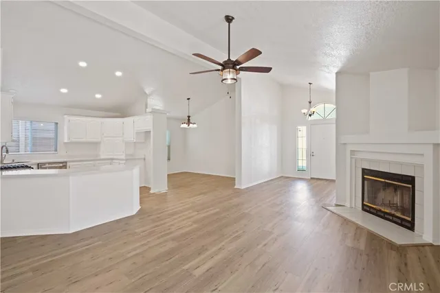 a view of a kitchen and an empty room with wooden floor