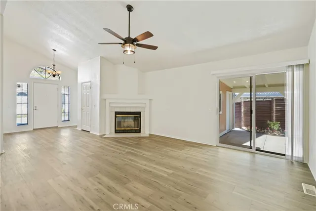 a view of a livingroom with a fireplace a ceiling fan and window
