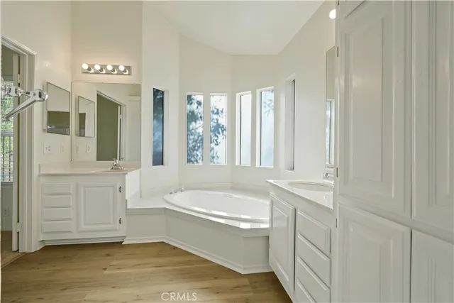 a bathroom with a tub a sink and a large mirror