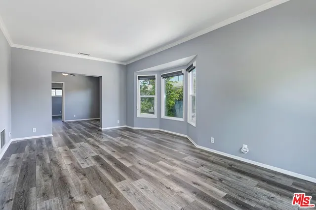 a view of an empty room with window and wooden floor