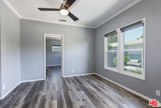 a view of empty room with wooden floor and fan