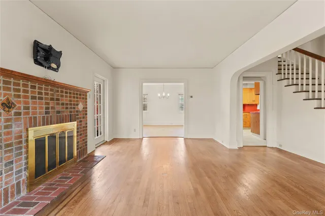 a view of an empty room with wooden floor and a fireplace