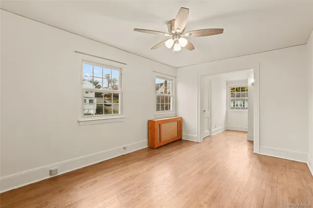 a view of an empty room with chandelier fan and wooden floor