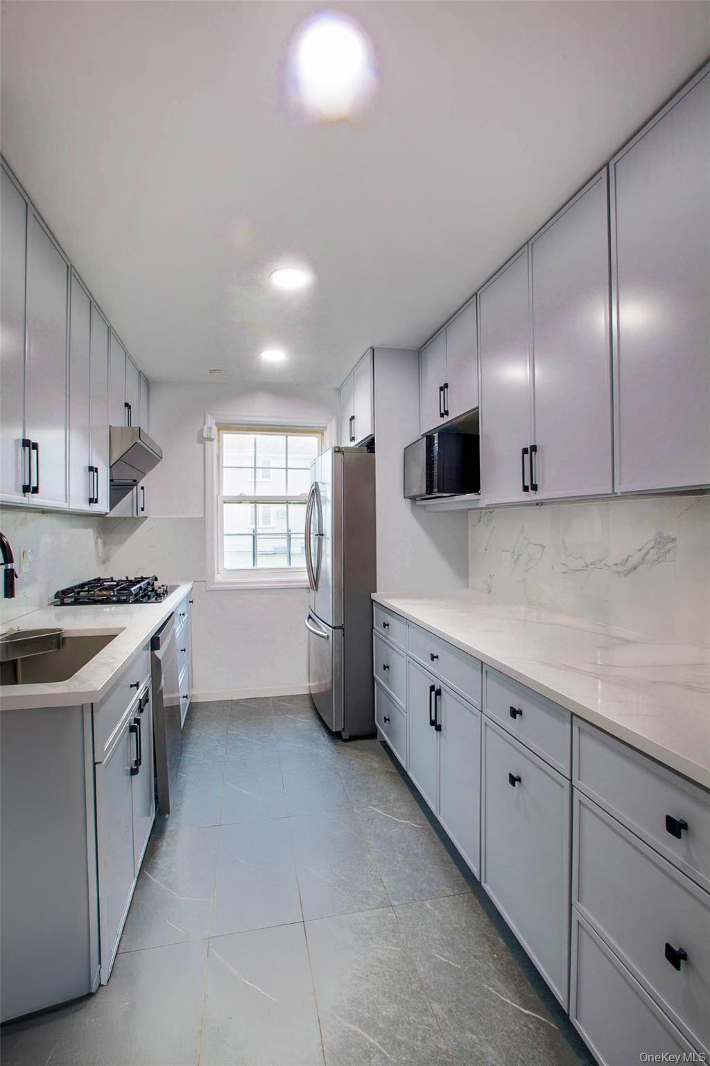 64-55 Springfield Boulevard, Unit 6455 Queens, NY 11364 - Photo 7 of 14 a kitchen with granite countertop white cabinets and white appliances