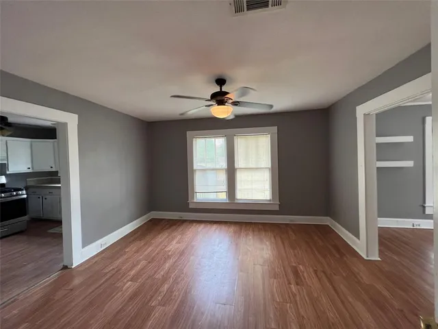 a view of an empty room with wooden floor and a window
