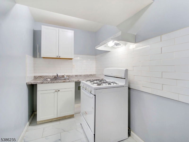 33 Kent Street Newark, NJ 07108 - Photo 8 of 12 a kitchen with a stove sink and cabinets