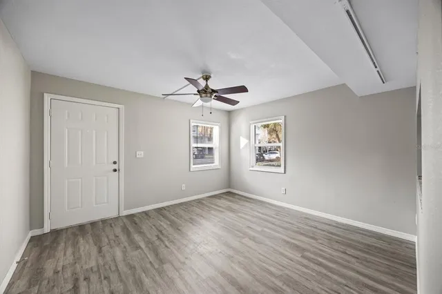 a view of empty room with wooden floor and fan