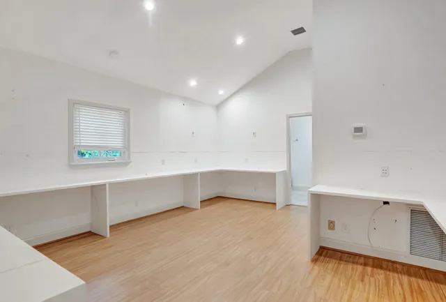 a view of a hallway with wooden floor and a bathroom