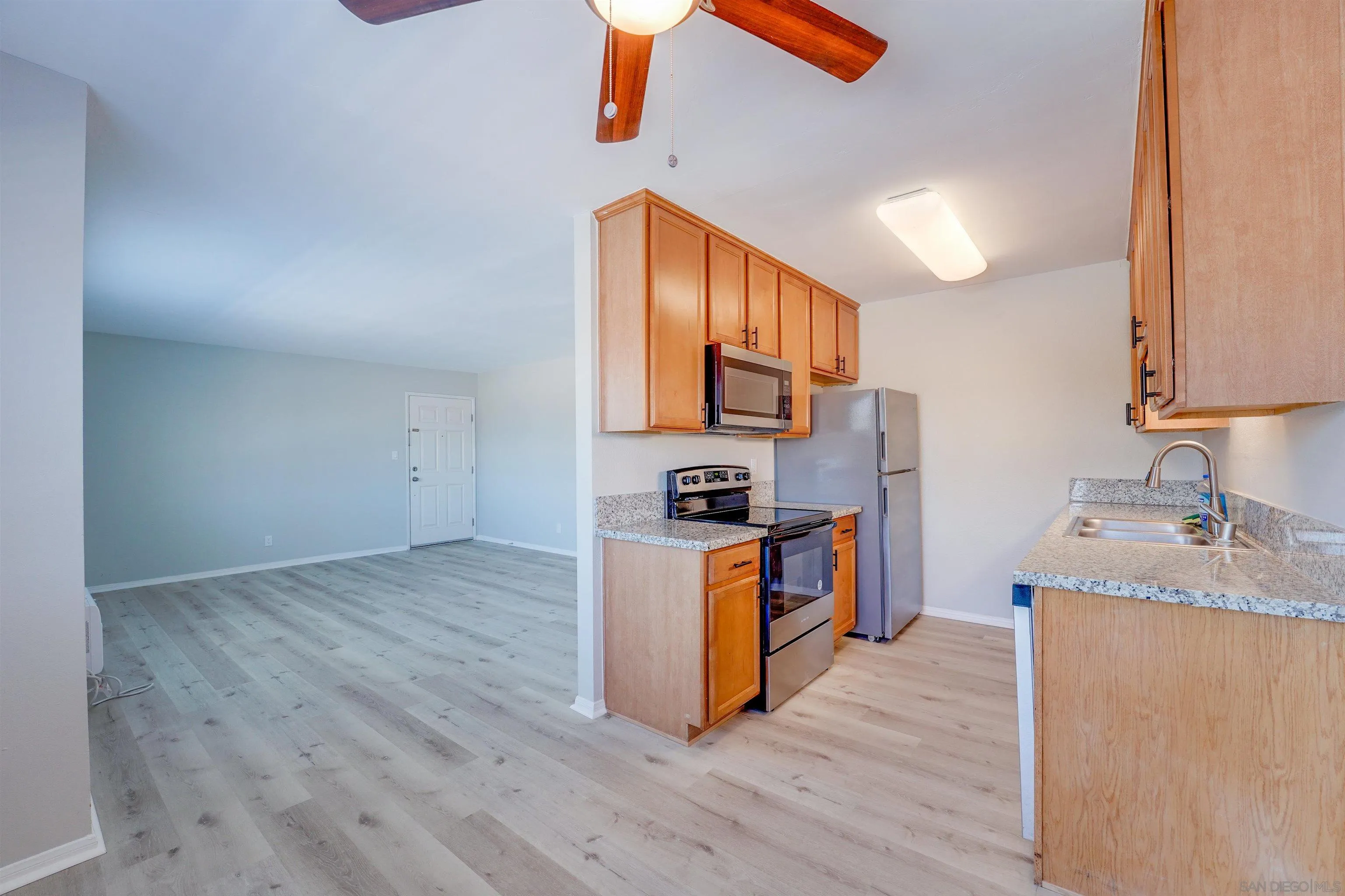 a kitchen with granite countertop a stove top oven a sink dishwasher and a refrigerator with wooden floor