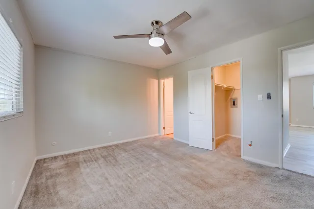 an empty room with closet and a ceiling fan