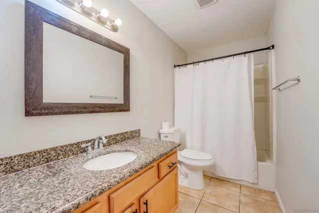a bathroom with a granite countertop sink a toilet and a mirror