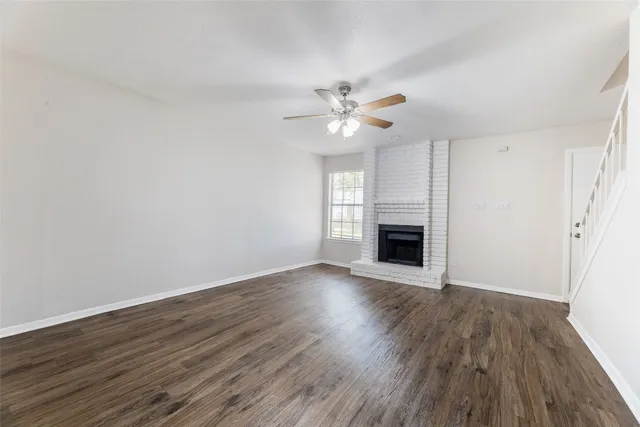 a view of empty room with a fireplace and wooden floor