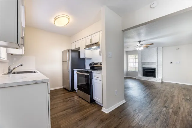 a kitchen with granite countertop a stove top oven and refrigerator