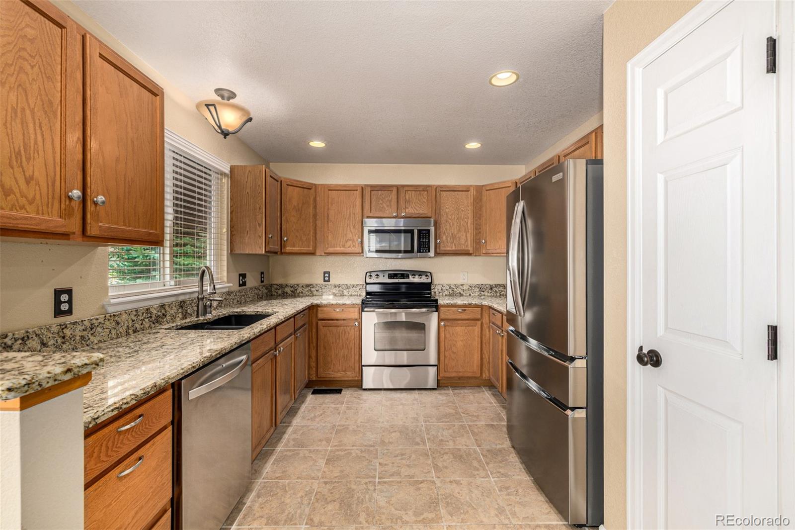 10244 Royal Eagle Street Highlands Ranch, CO 80129 - Photo 16 of 46 a kitchen with stainless steel appliances granite countertop a refrigerator sink and cabinets