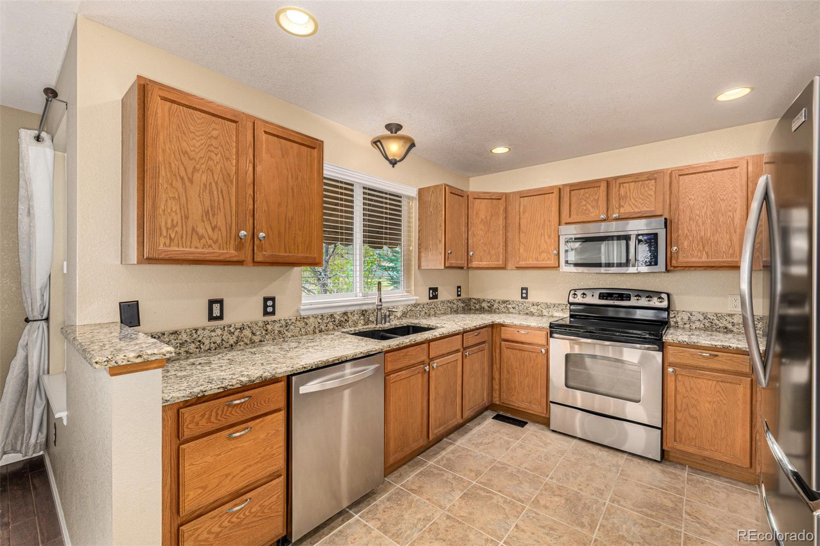 10244 Royal Eagle Street Highlands Ranch, CO 80129 - Photo 18 of 46 a kitchen with stainless steel appliances granite countertop a sink stove and refrigerator