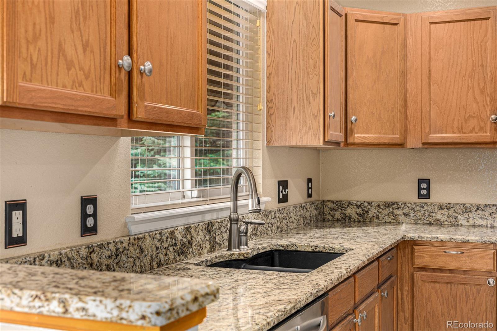 10244 Royal Eagle Street Highlands Ranch, CO 80129 - Photo 19 of 46 a kitchen with granite countertop a sink and a window