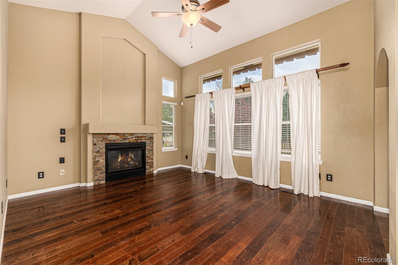 10244 Royal Eagle Street Highlands Ranch, CO 80129 - Photo 10 of 46 an empty room with wooden floor fireplace and windows
