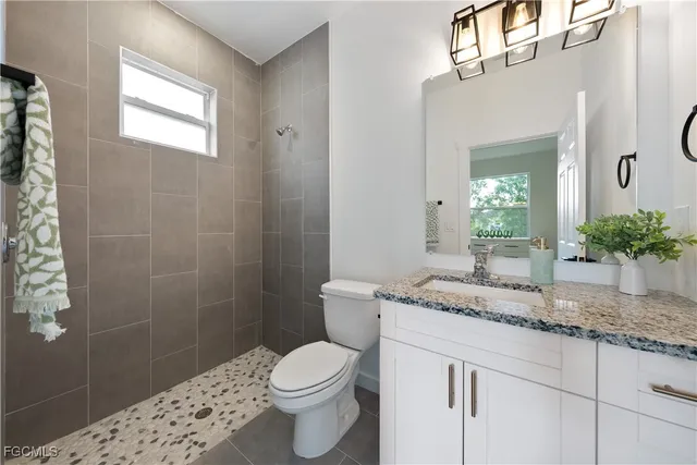 a bathroom with a granite countertop sink a toilet and shower