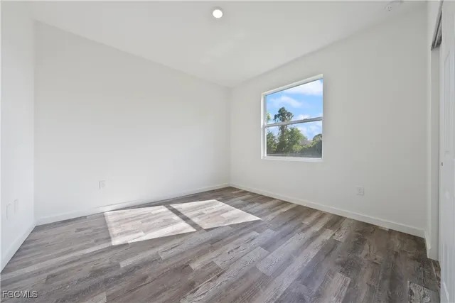 an empty room with wooden floor and window