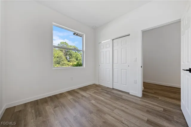 an empty room with wooden floor closet and windows