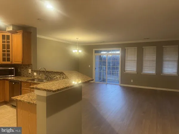 a view of a kitchen counter top space with wooden floor and fan