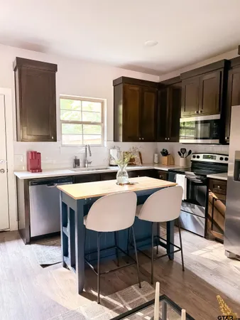a kitchen with stainless steel appliances kitchen island granite countertop a sink refrigerator and cabinets