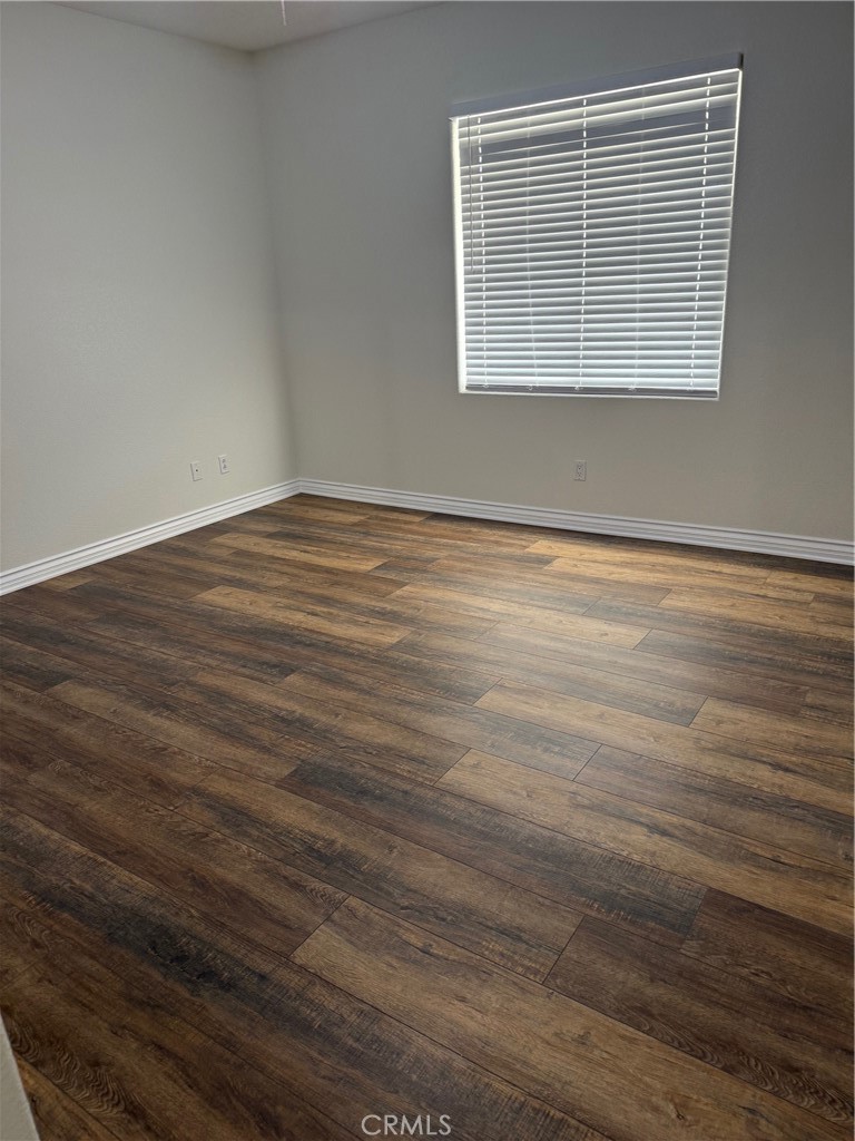18453 Ranchero Road Hesperia, CA 92345 - Photo 11 of 17 a view of an empty room with wooden floor and a window