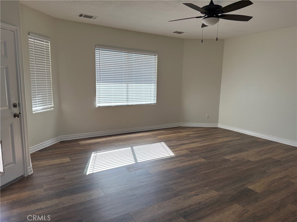 18453 Ranchero Road Hesperia, CA 92345 - Photo 3 of 17 an empty room with wooden floor fan and windows